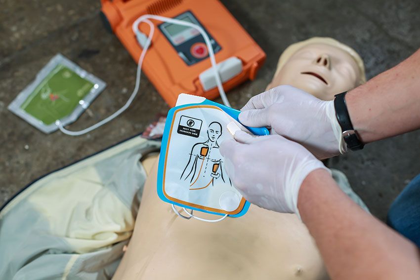 An EMT using an automatic external defibrillator in conducting a basic cardiopulmonary resuscitation to a dummy on the street