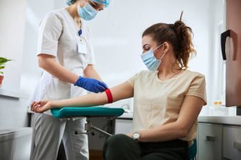 Image of a phlebotomist applying a venous tourniquet to a patient's arm.