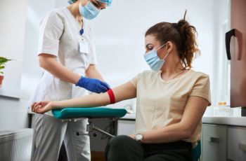 Image of a phlebotomist applying a venous tourniquet to a patient's arm.